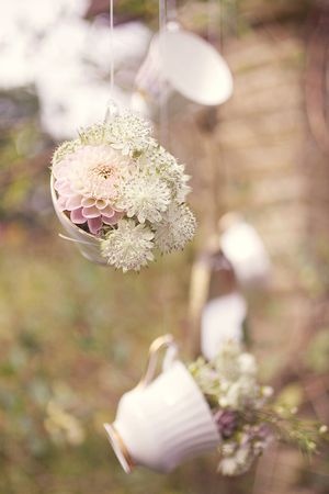 Pretty tea cups filled with flowers hanging from above