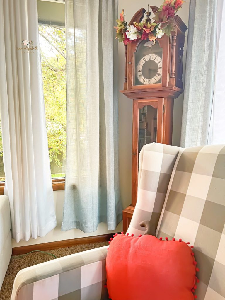 Grandfather clock with a pumpkin shaped pillow in a decorated living room