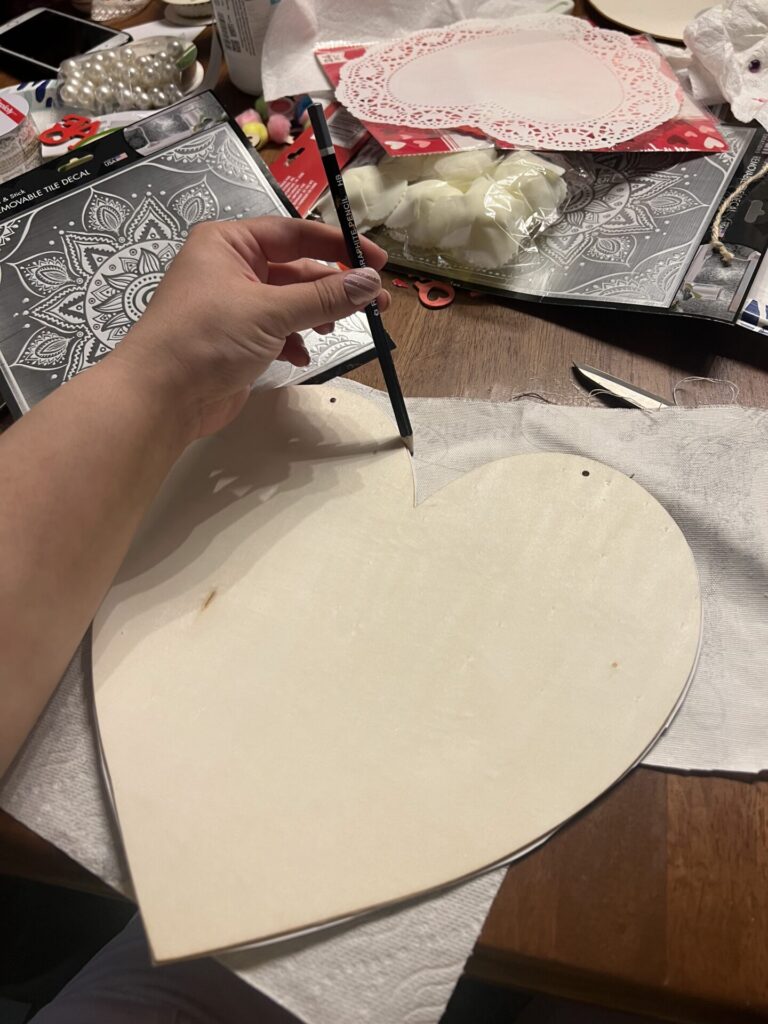 tracing the wooden heart shape onto the back of the scrapbooking paper