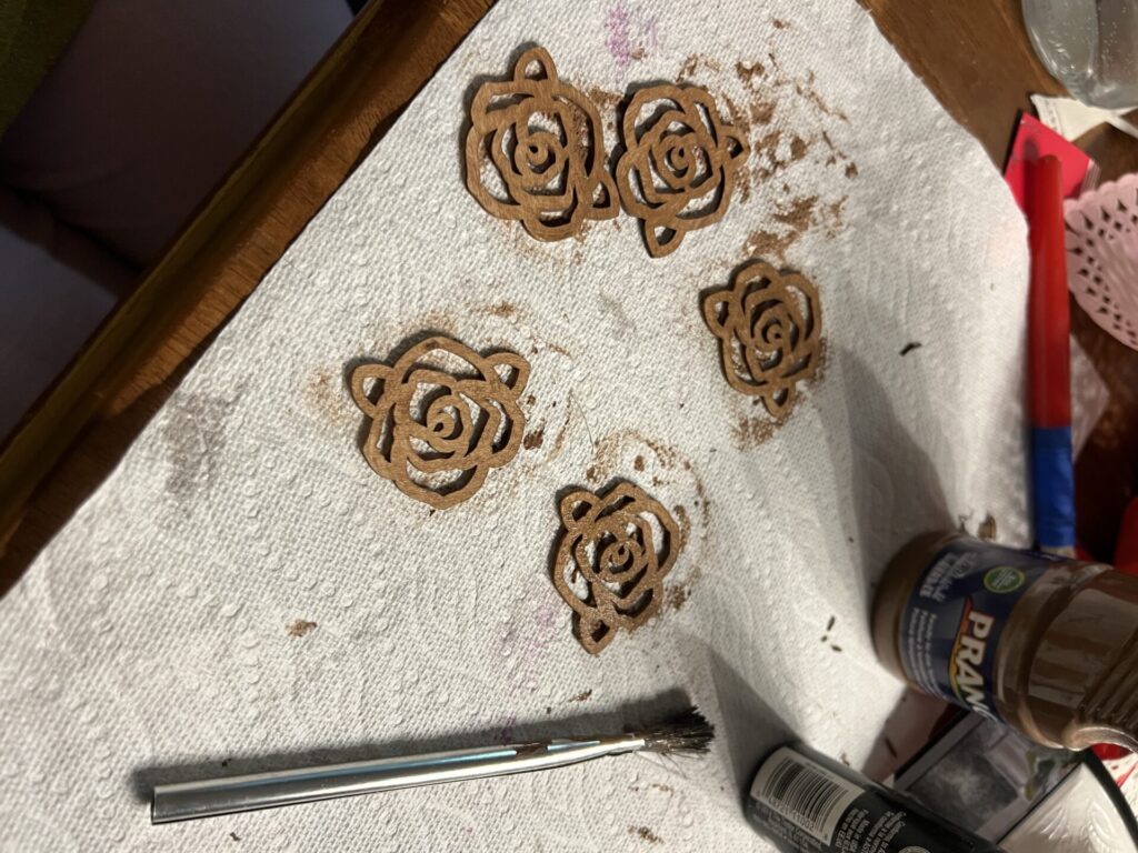 wood rose appliqués on a piece of paper towel painted brown