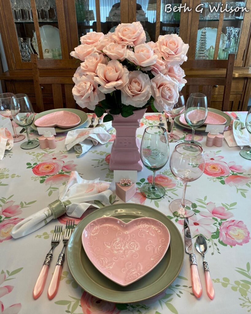 a pink themed valentines day table with roses and wine glasses
