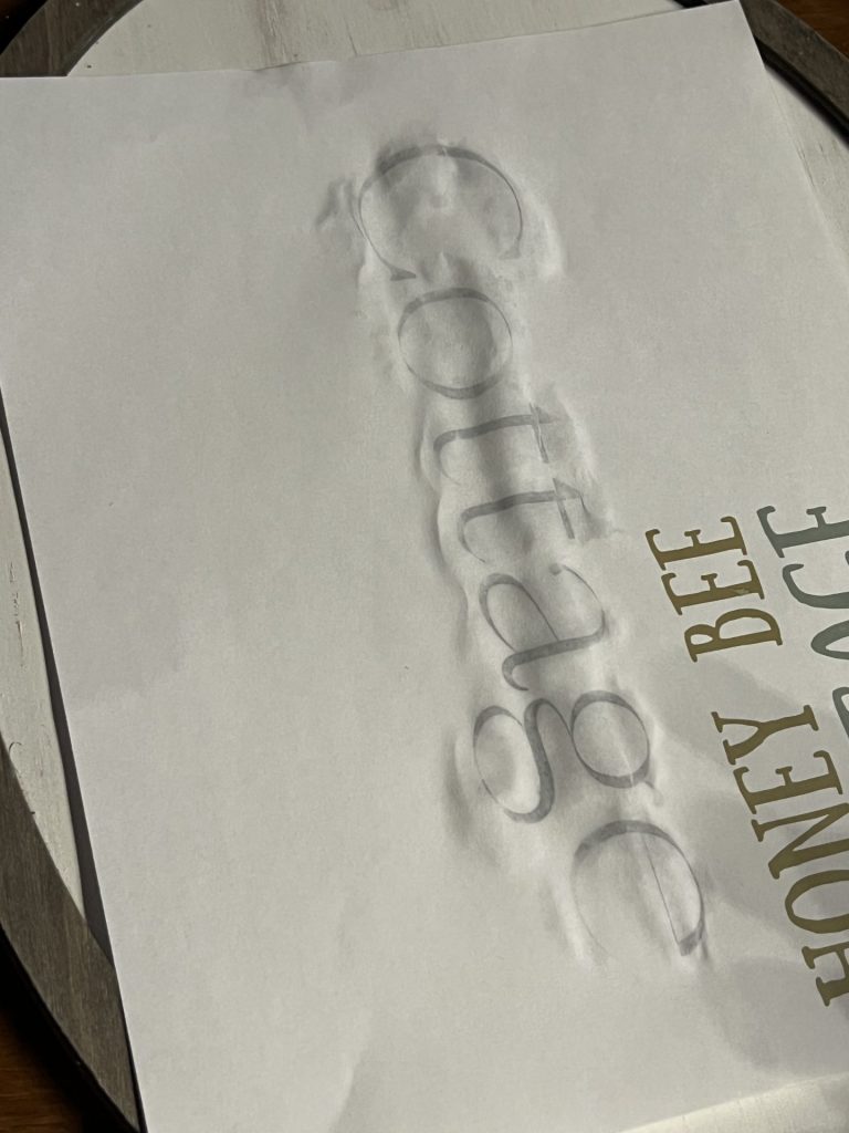 lightly dampened wording on a piece of paper laying on the vintage wooden sign