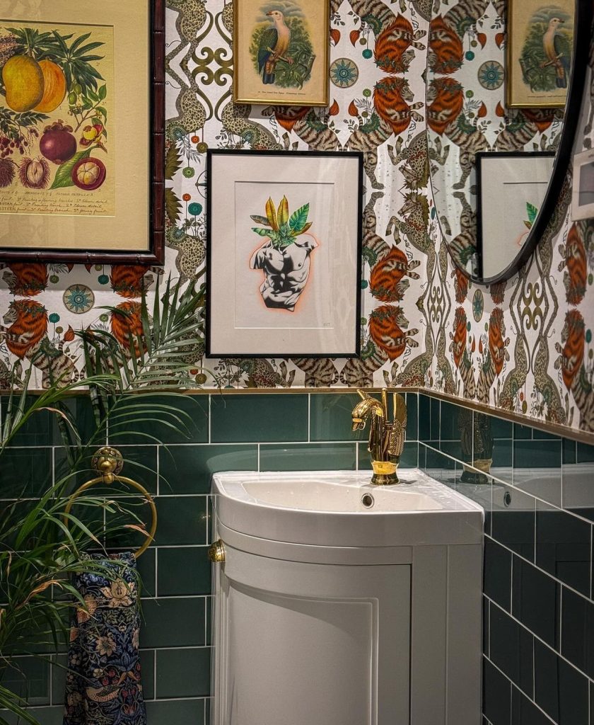 fun vintage bathroom with a gold swan faucet surrounded by green tile and lion wallpaper