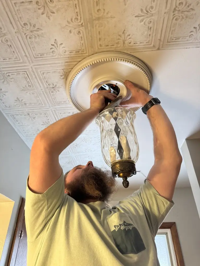 man installing an antique light fixture