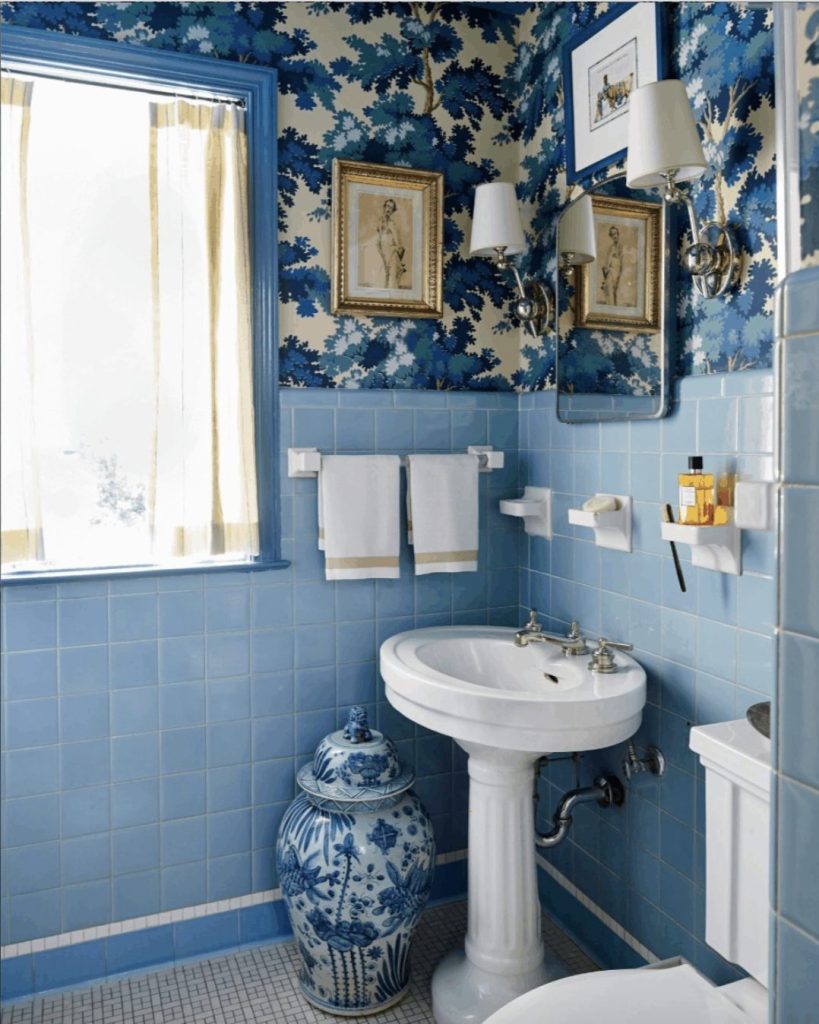 blue tile bathroom with a white pedestal sink and blue patterned wallpaper