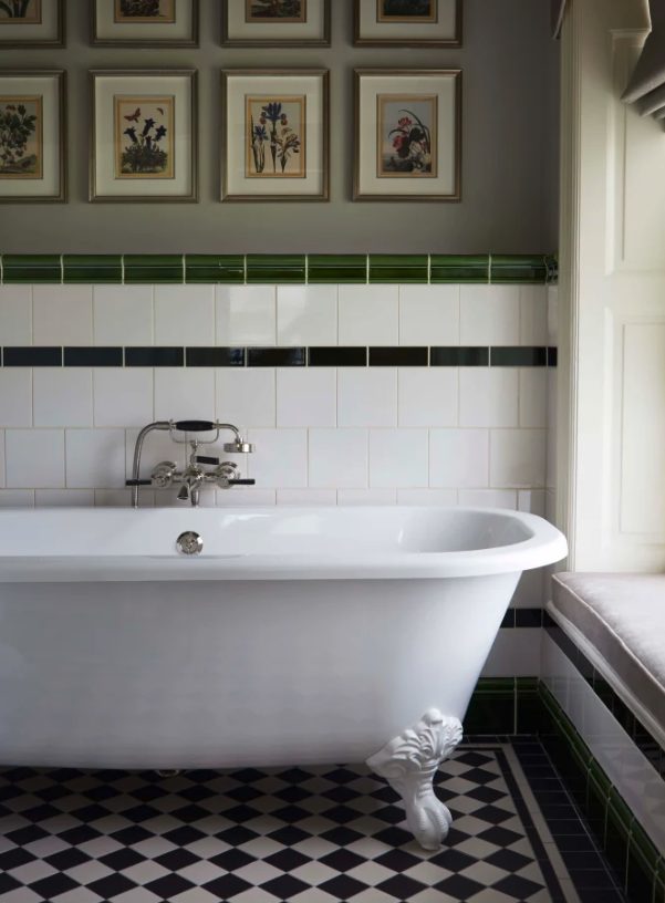 green and white tile bathroom view with white tub and a collage of photos on the wall