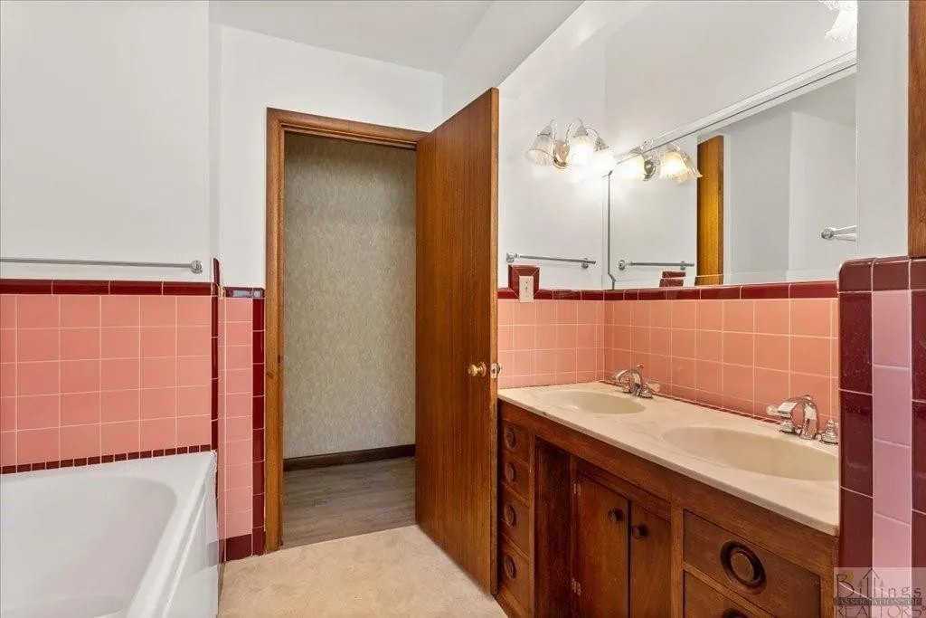 the before view of a pink tile bathroom with a wood vanity
