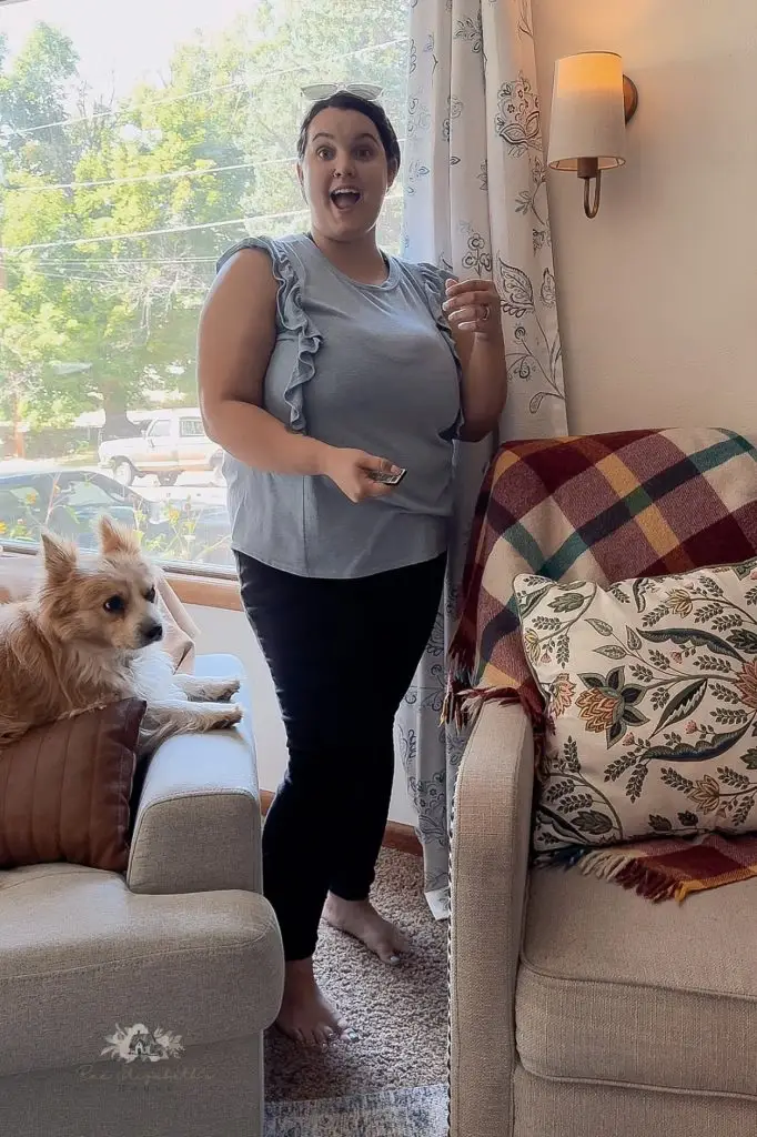 woman smiling and excited in a living room next to a wall sconce