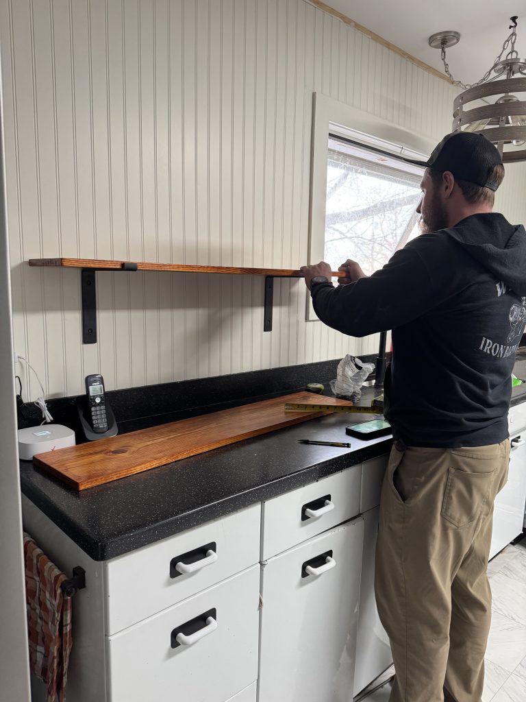 man putting up a kitchen open shelf on the wall