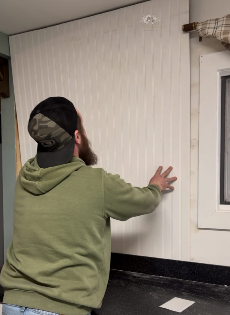 man putting up a piece of bead board backing